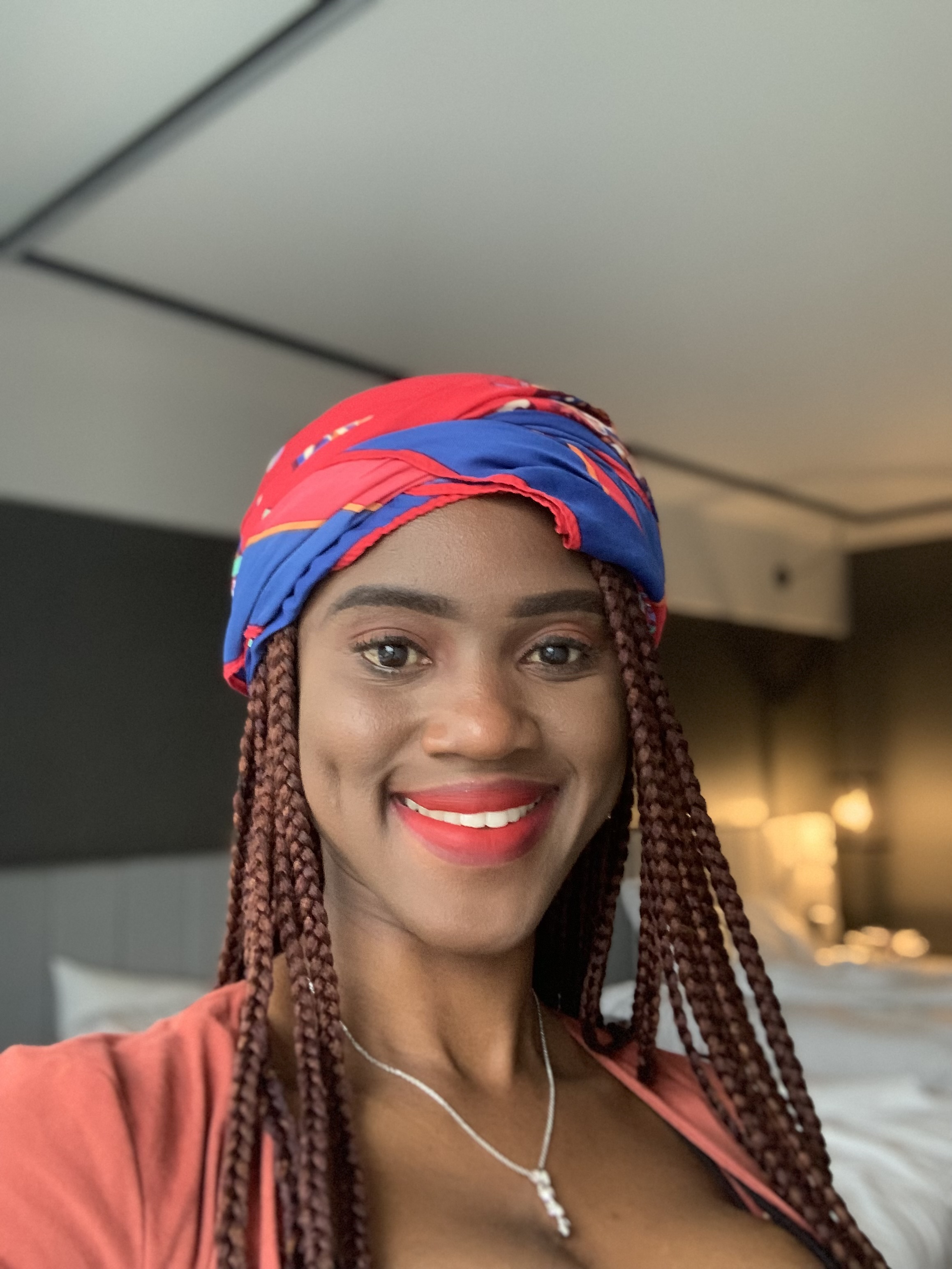 Jayne Adole smiles at camera wearing colorful head wrap.